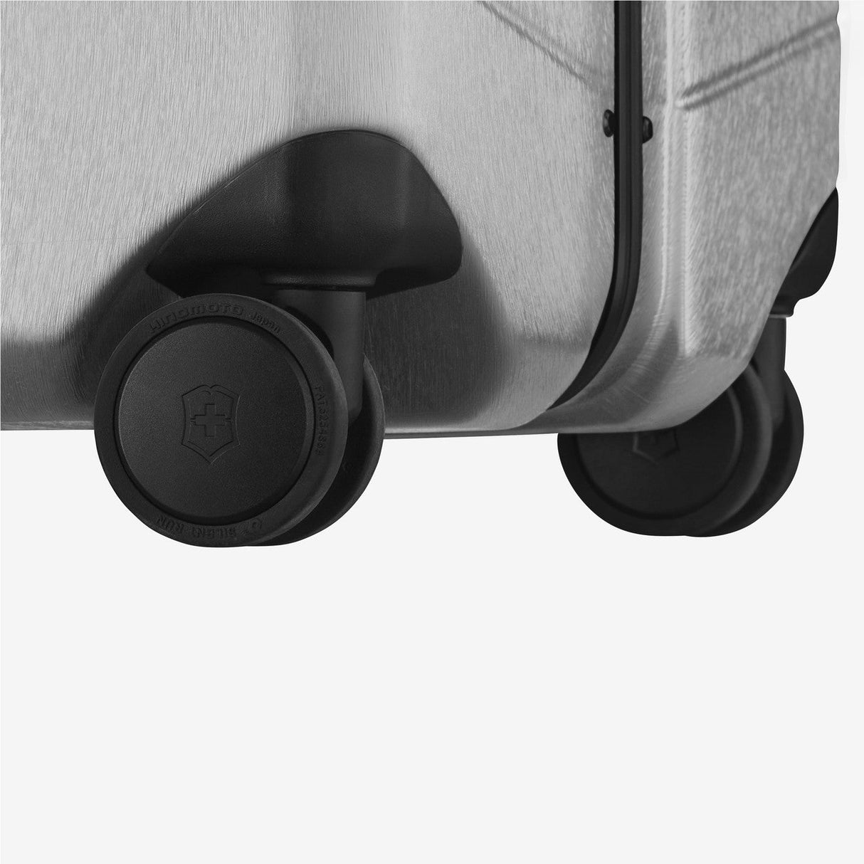 Suitcase wheels attached to the corner of a hard-shell luggage.