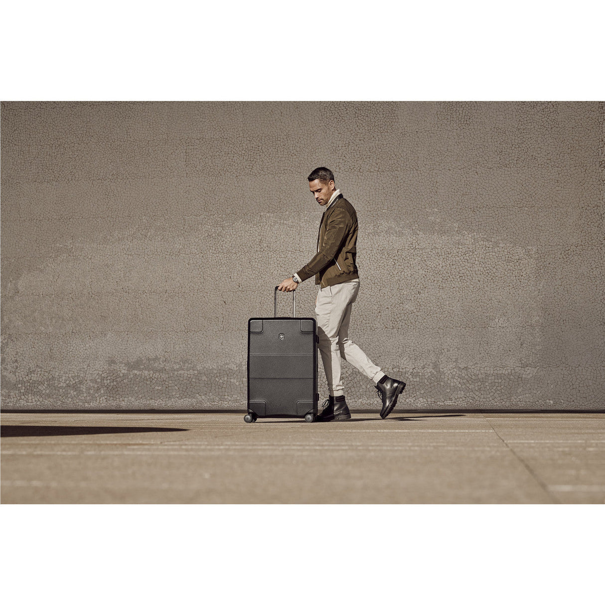 Wheeled suitcase being pulled by a stylishly dressed man.