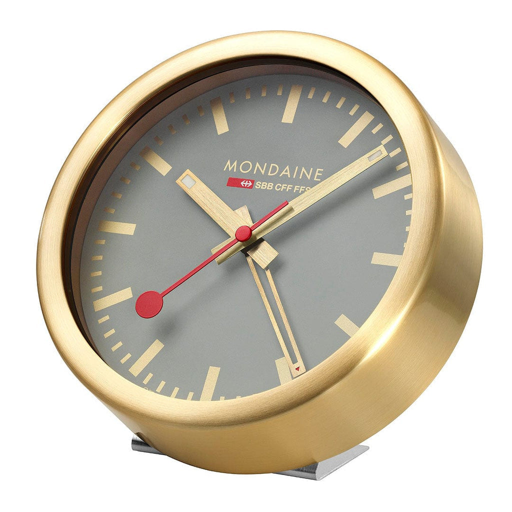 Gold-colored analog desk clock with a gray face and red hands.