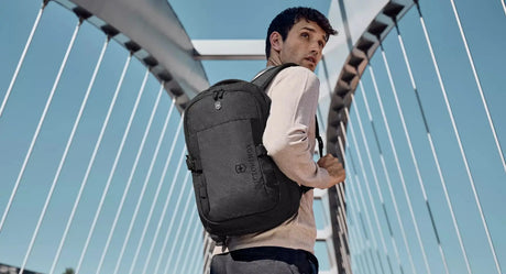 Sleek gray backpack worn by a person on a bridge.