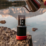 Portable coffee maker or espresso device sitting on a rock.