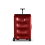 Red hardshell rolling suitcase with horizontal ridges and a retractable handle.