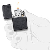 Lit Zippo lighter with intricate engraved design on its black metal casing.
