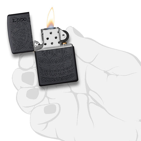 Lit Zippo lighter with intricate engraved design on its black metal casing.
