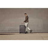 Wheeled suitcase being pulled by a stylishly dressed man.