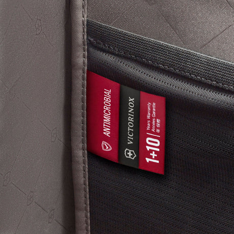 Red fabric label with brand logos attached to a dark textile surface.