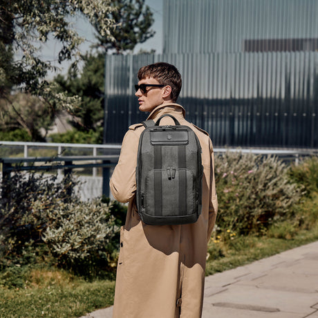 Gray backpack worn by a person in a beige coat.