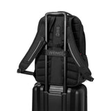 Black backpack with a luggage strap designed to fit over a suitcase handle.