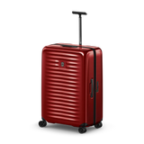 Red hardshell rolling suitcase with horizontal ridges and a retractable handle.