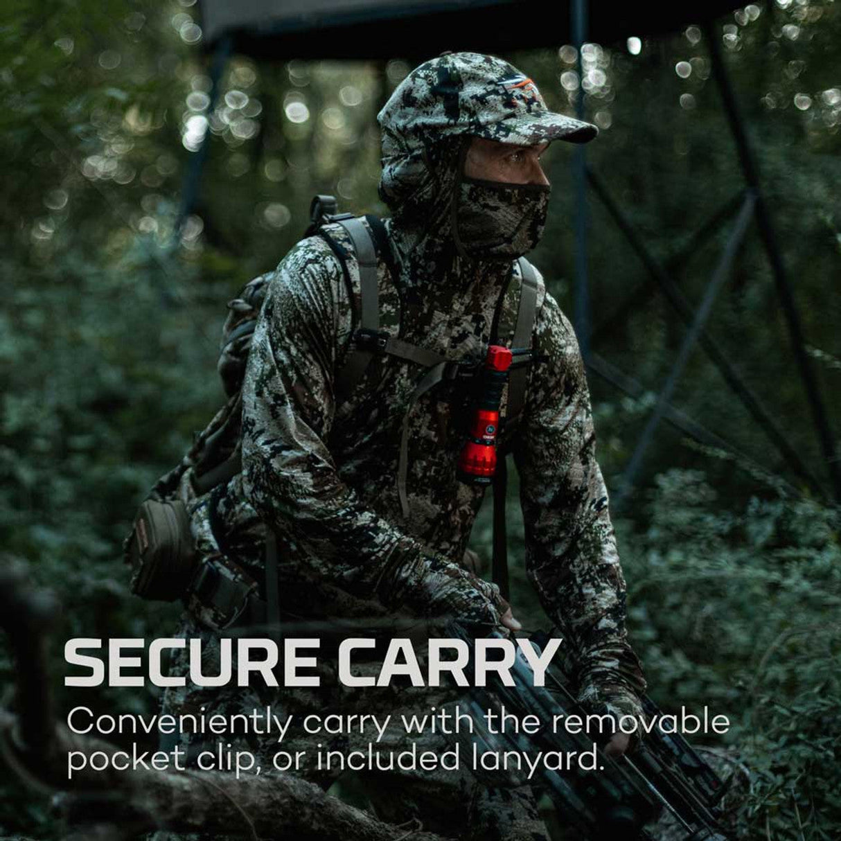 Camouflaged soldier in tactical gear holding a weapon in a forest setting.