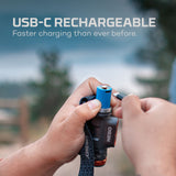 USB-C rechargeable device, likely a flashlight or portable light, being held and charged outdoors.