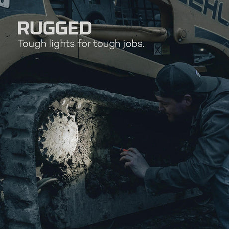 Bright spotlight illuminating a dark, rough surface while a person examines it closely.