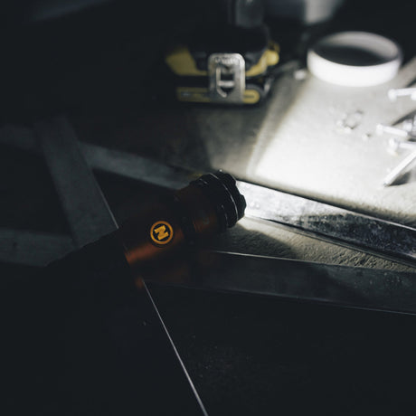 Black flashlight with an orange power button.