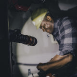 Man wearing a plaid shirt and hat speaking into a microphone.