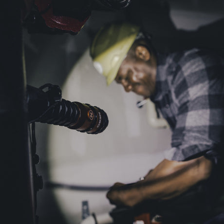 Man wearing a plaid shirt and hat speaking into a microphone.
