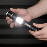 Flashlight labeled ’NEBO’ being held and illuminated in someone’s hand.