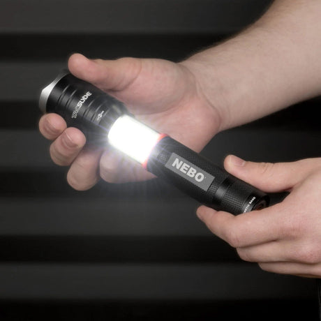 Flashlight labeled ’NEBO’ being held and illuminated in someone’s hand.