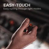 A hand holding a small electronic device or button with an orange indicator light.