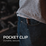 Pocket clip attached to the edge of a jeans pocket, partially visible beneath a gray shirt.