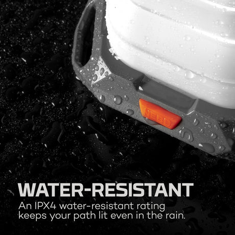 Water-resistant headlamp with visible orange light and water droplets on its surface.